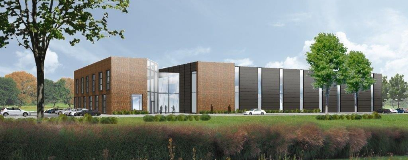 A computer generated render of an industrial building, planned to be built on the King's Lynn Enterprise park. It shows greenery, trees, and a long, rectangular building with orange bricks and dark cladding.